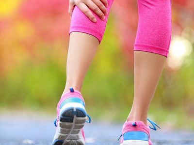 Woman running clutching calf muscle injury after spraining it wh